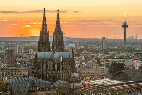 Kölner Dom mit Hauptbahnhof untergehender Sonne am Horizont